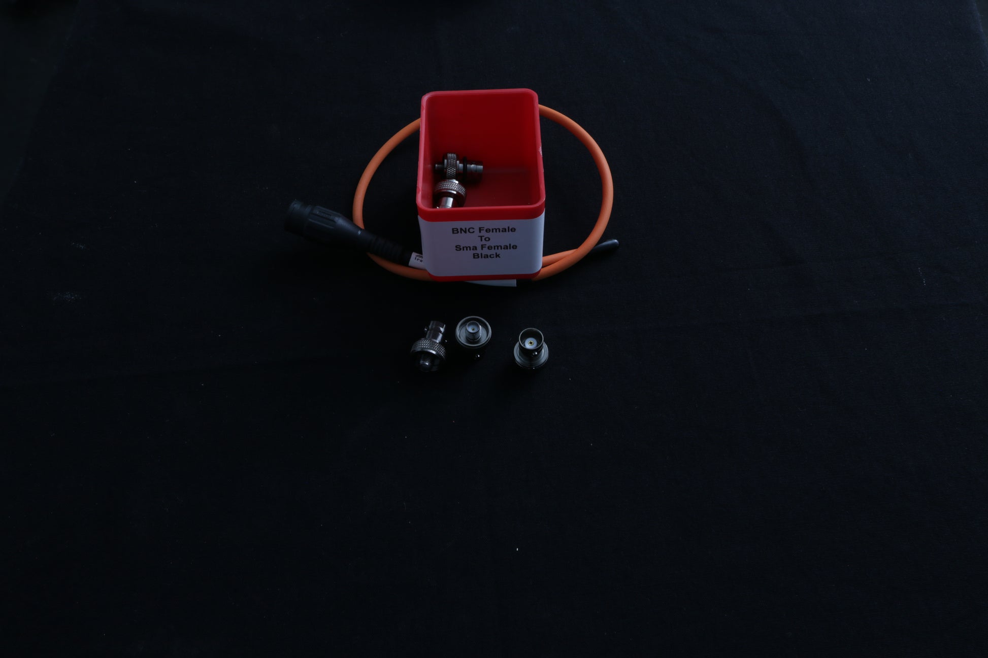 Small red box with SMA female to BNC female adapters