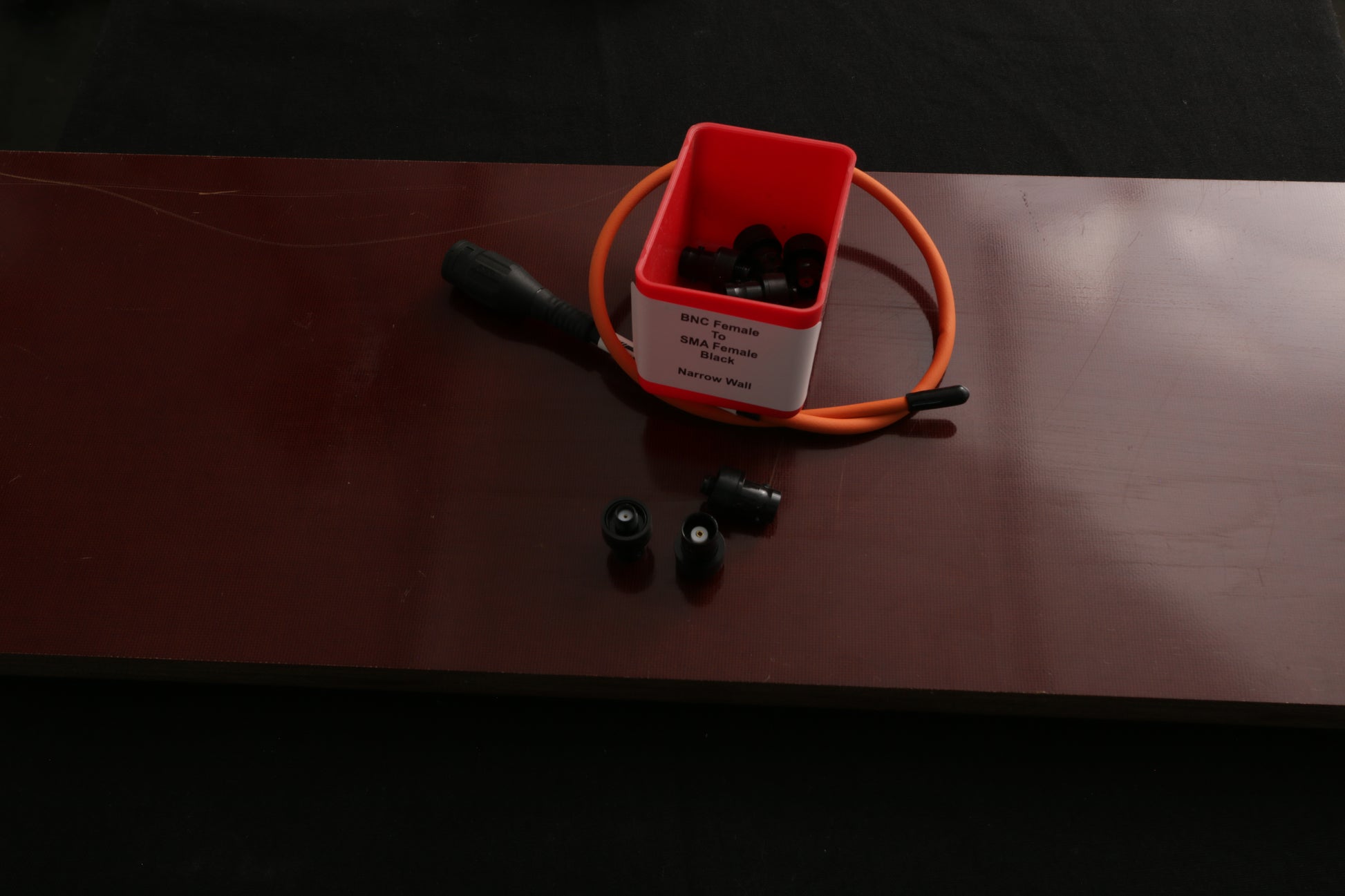 SMA female to BNC female narrow wall adapter on dark background with Maximus antenna